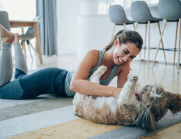  A woman plays with her dog on the living room rug
